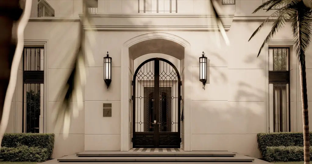 Stately building entrance with decorative door and wall lights, featuring a sepia tone.