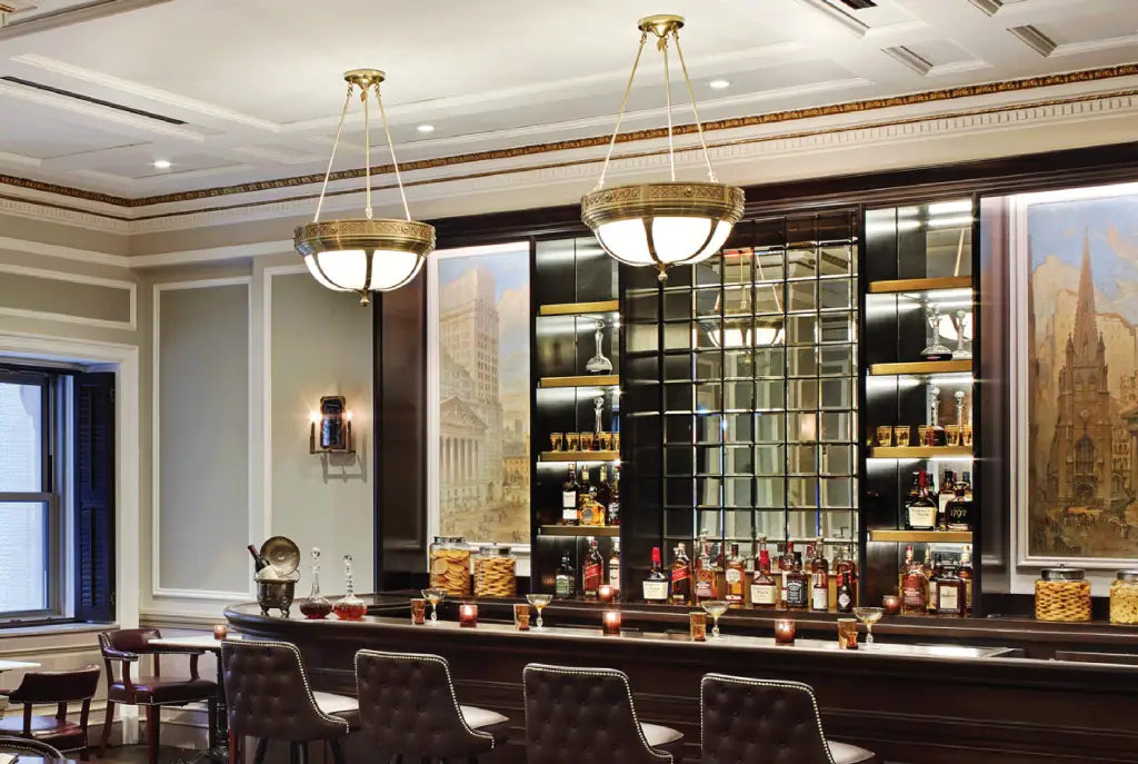 Luxury bar with high-end liquor bottles, elegant decor, lighting, and framed artworks.