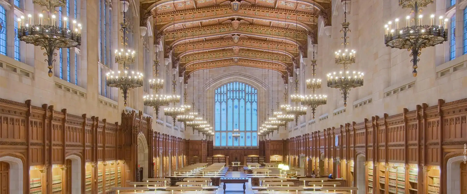Ornate library reading room with numerous chandeliers and wooden paneling.
