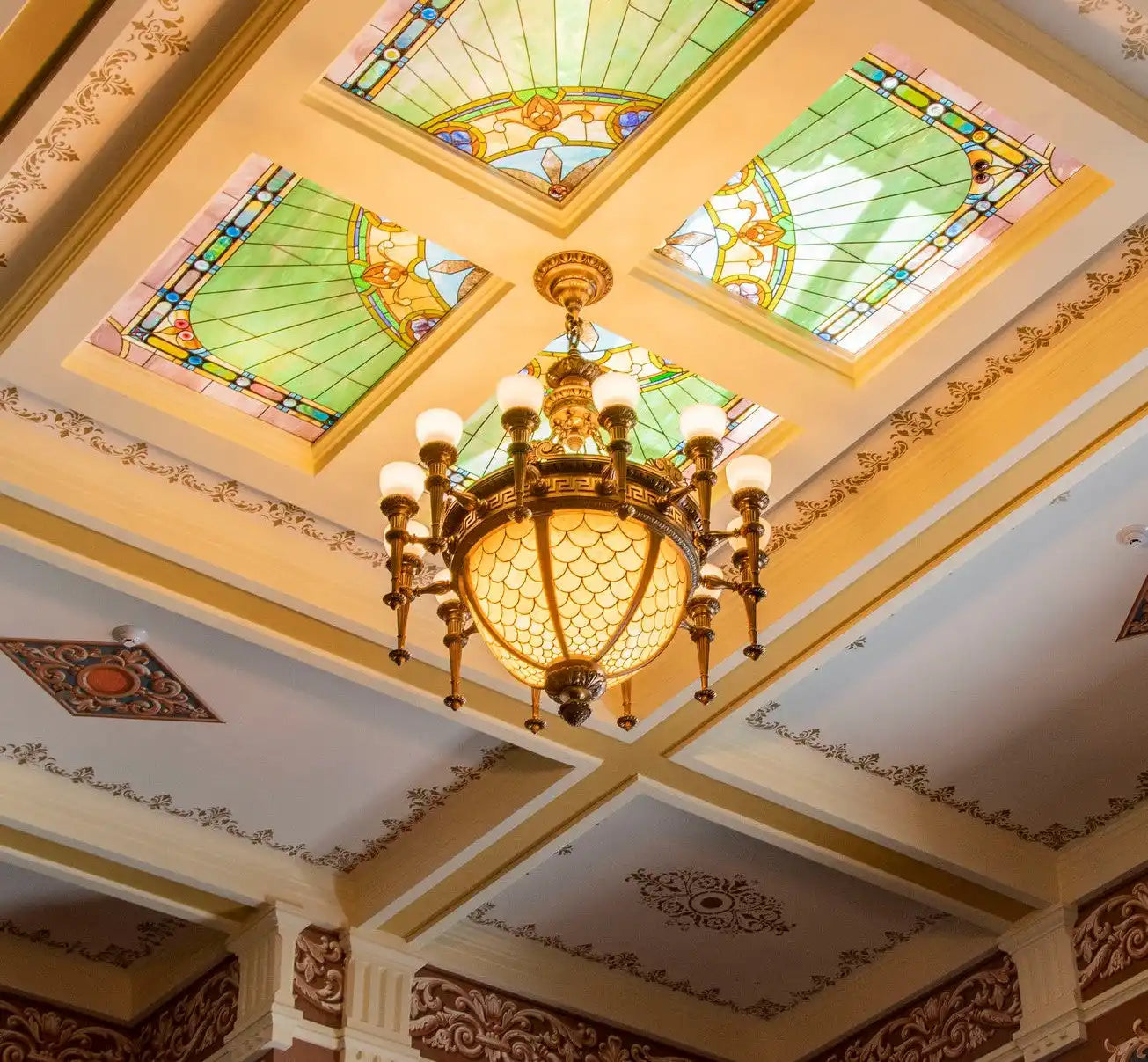 Ornate brass chandelier with multiple lights and a decorative glass bowl.