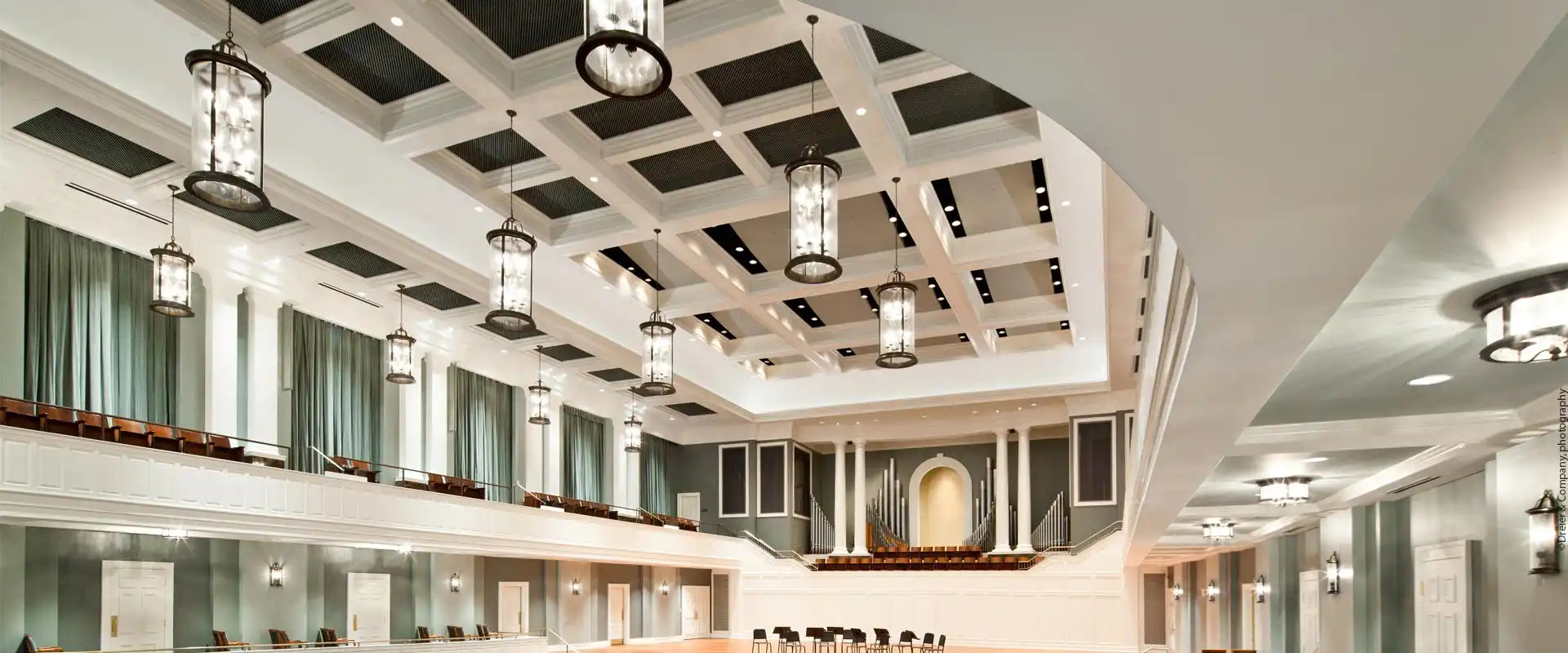 A grand, ornate hall with high ceilings, decorative lighting, and a stage.