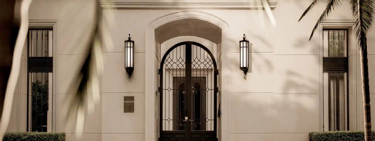 Elegant building facade with an arched, ornate metal gate and tall, decorative windows.