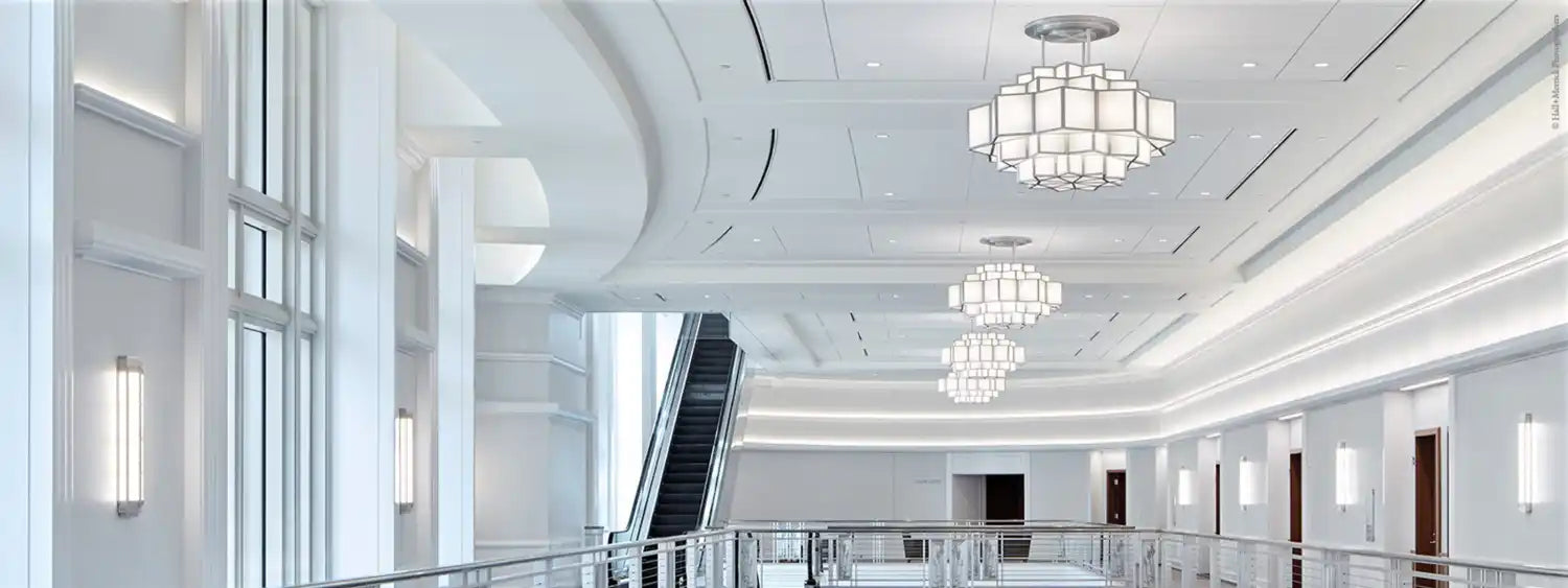 A modern, brightly lit interior hallway with an escalator and decorative chandeliers.