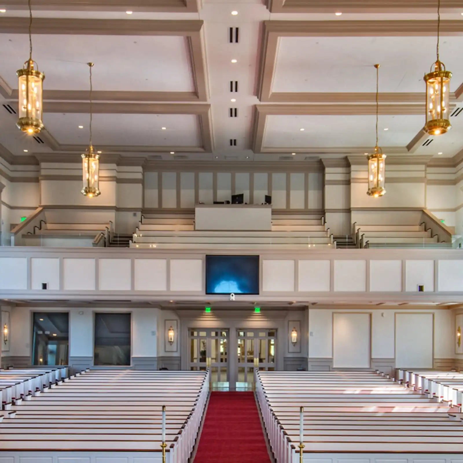 A large, well-lit church interior with rows of white pews and a red carpeted aisle.