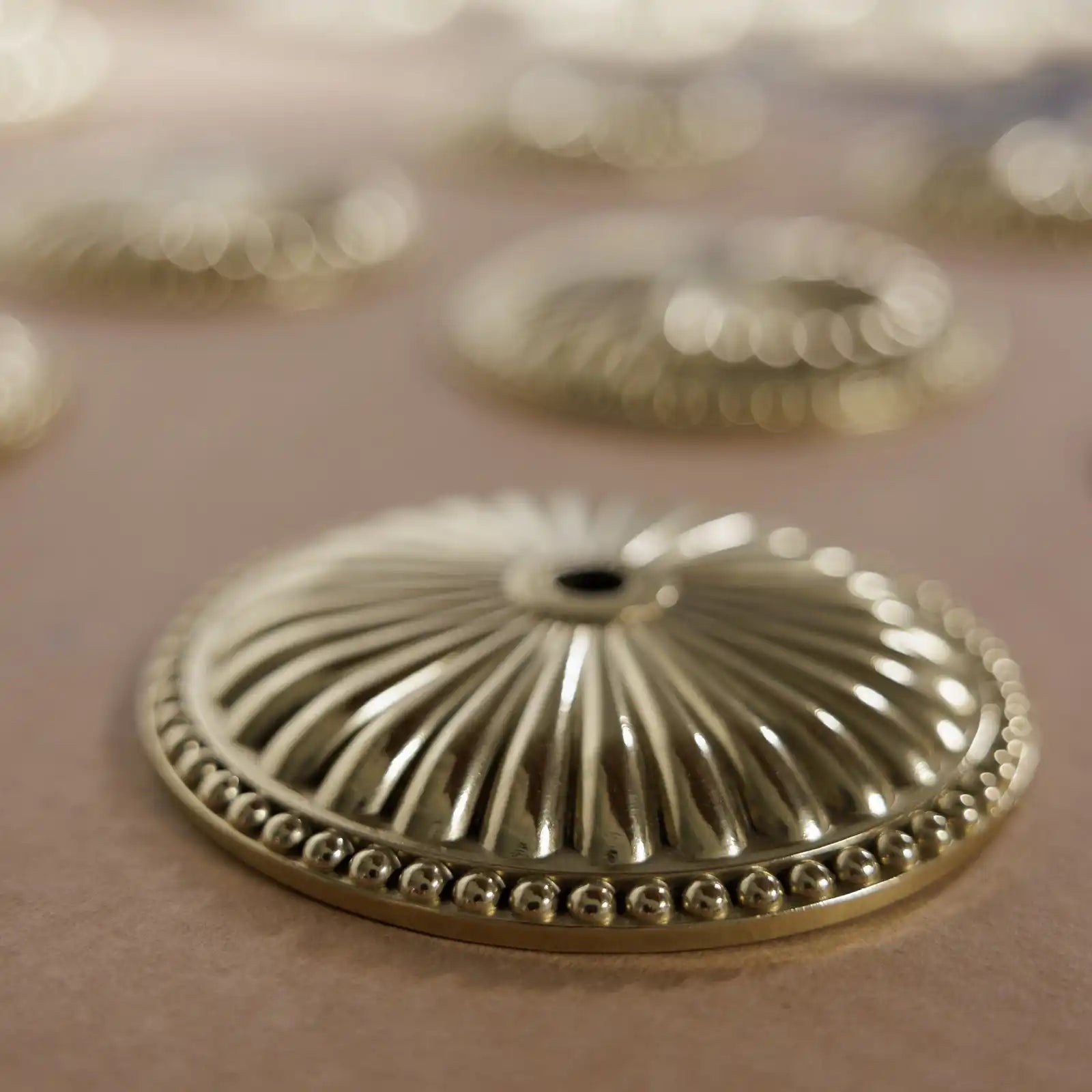 Ornate gold-colored metal escutcheon with a beaded edge.